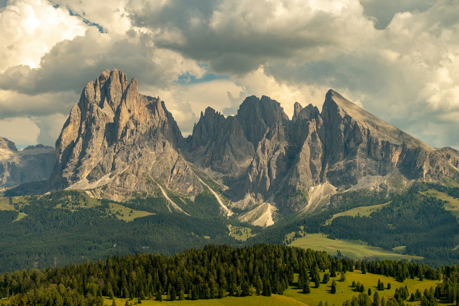 The jagged rock walls of Sassolungo rising above alpine meadow, Dolomites