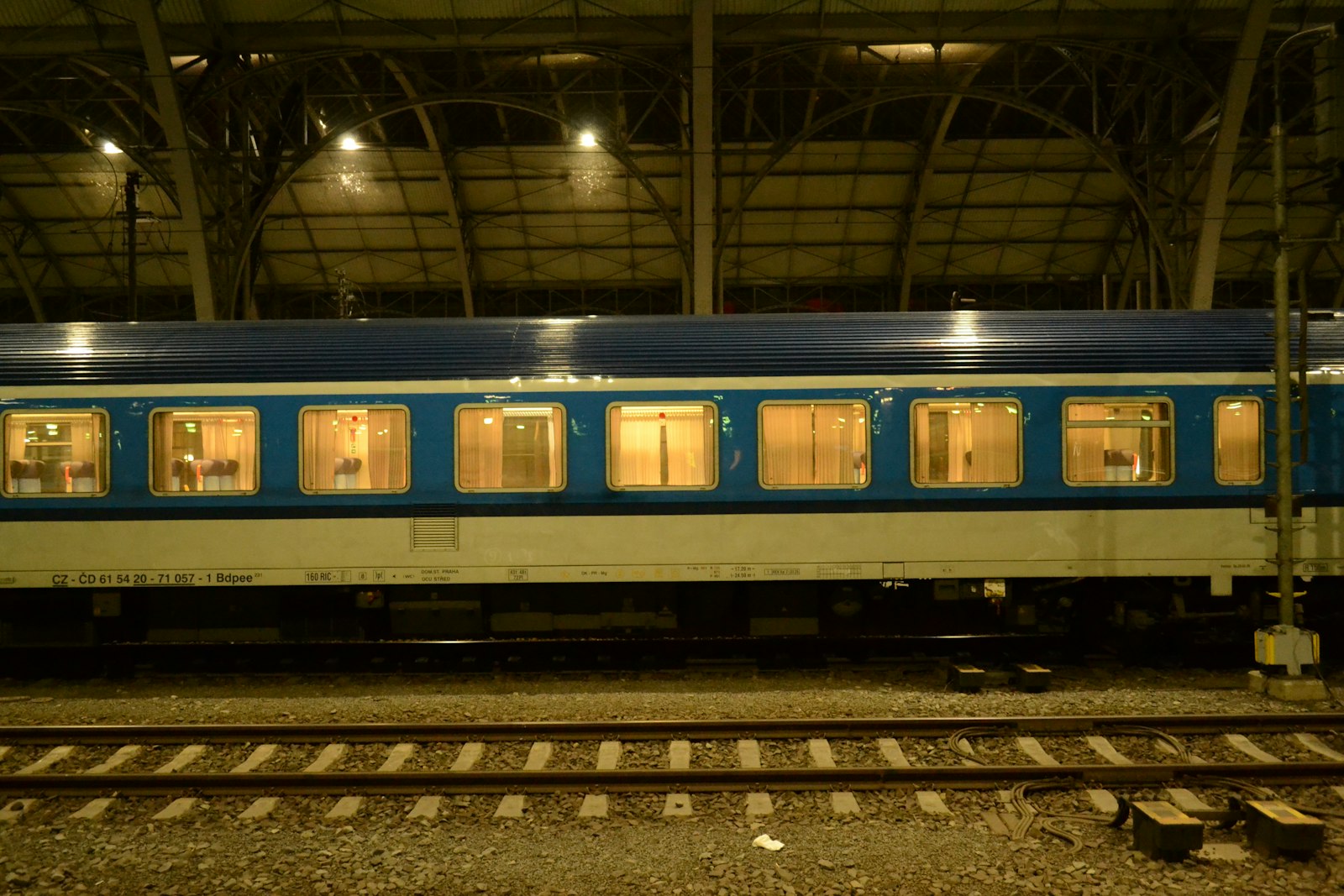 A night train with lit windows waiting at a platform after dark