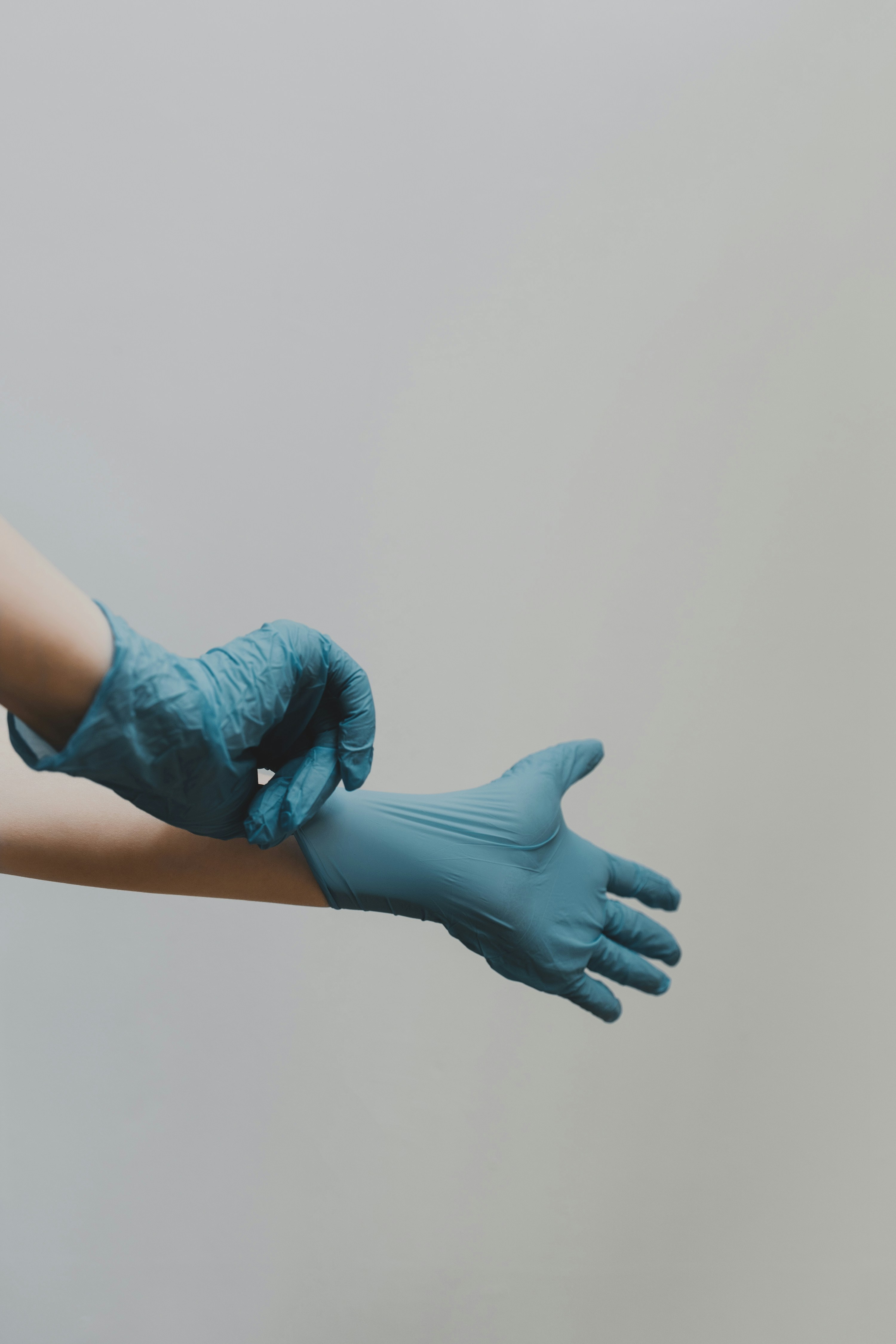 A clinician pulling on blue medical gloves
