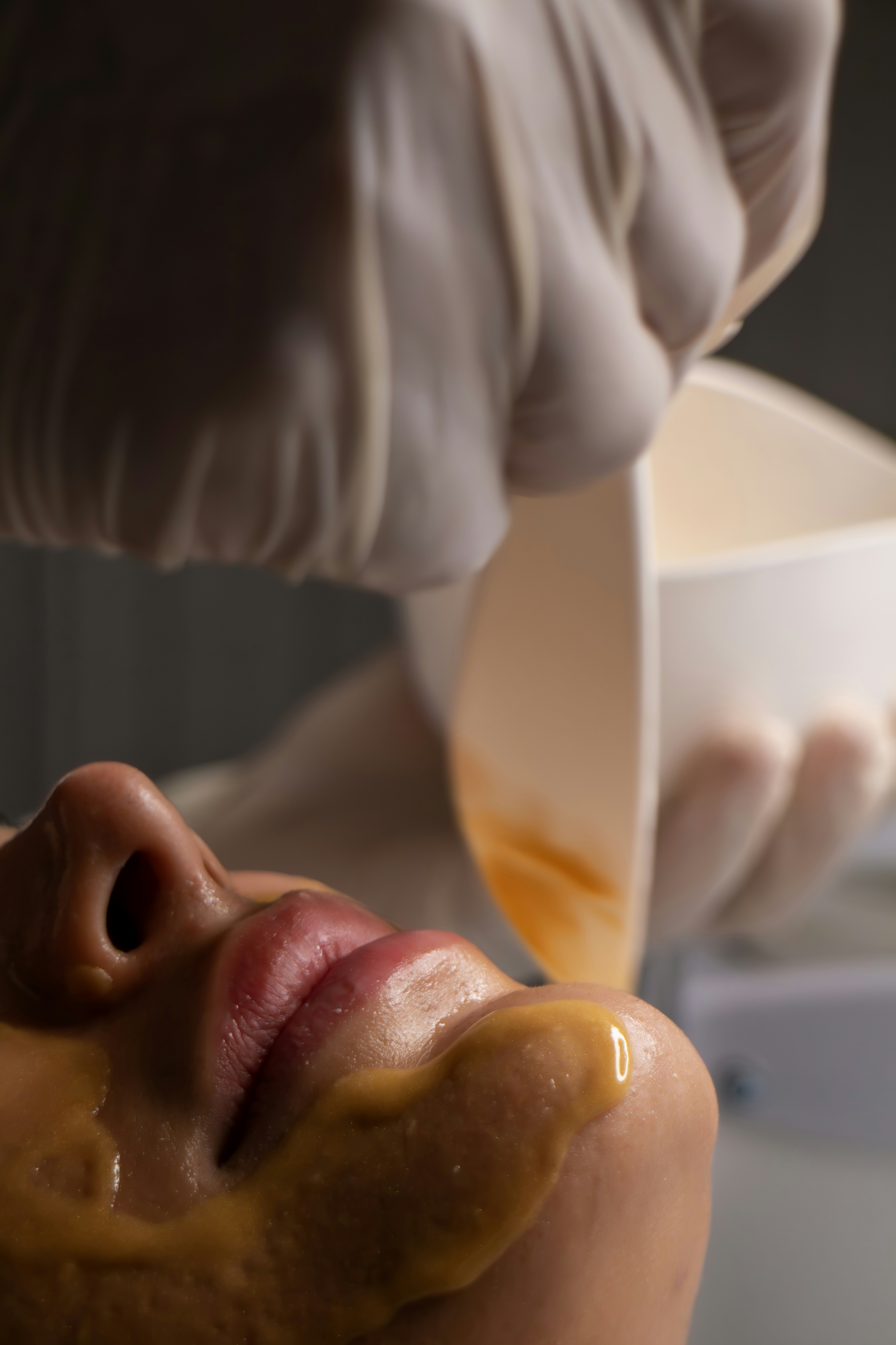 A beautician applying a facial mask to a client's face