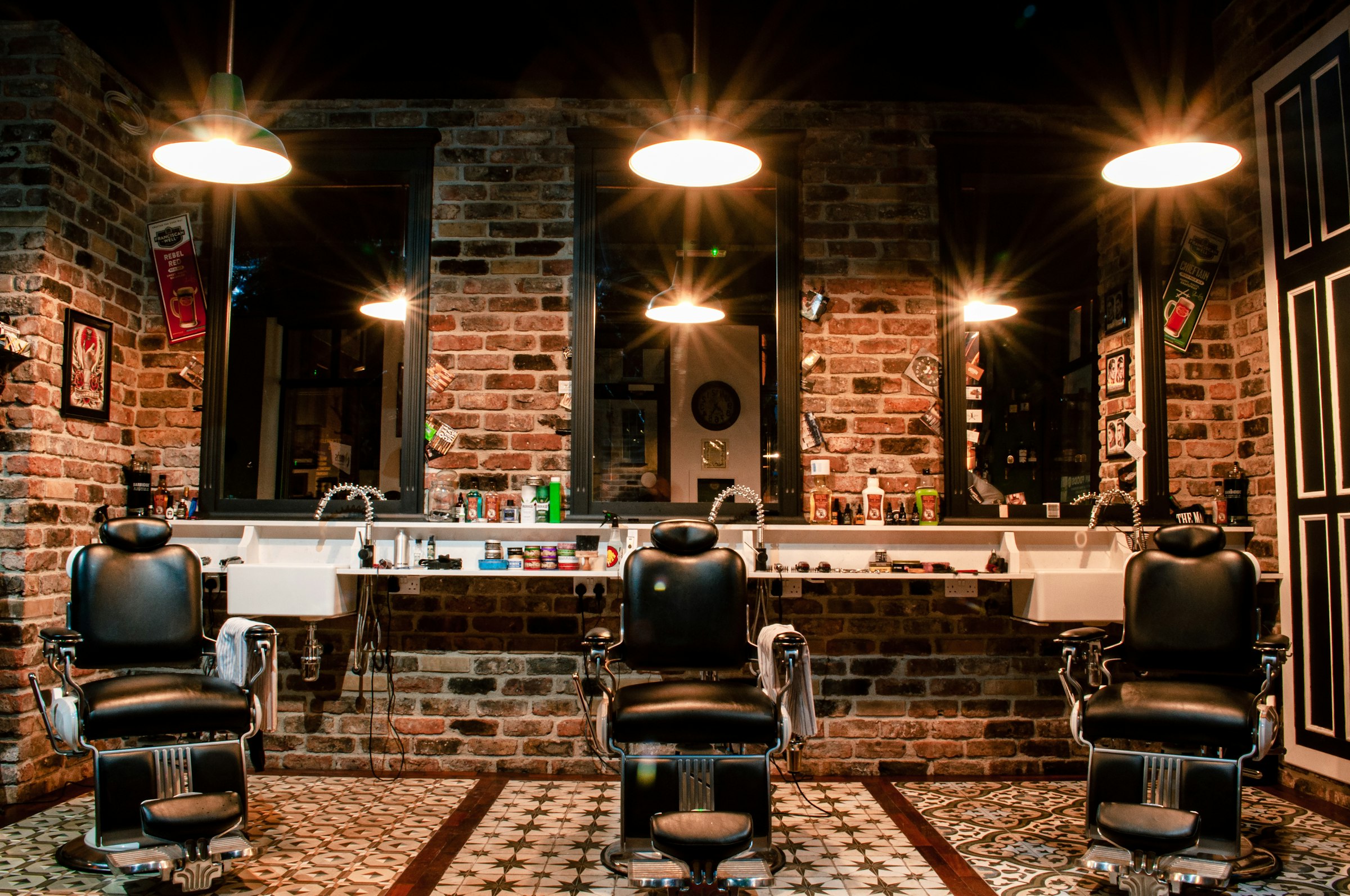 A traditional barbershop interior with leather chairs and a brick wall