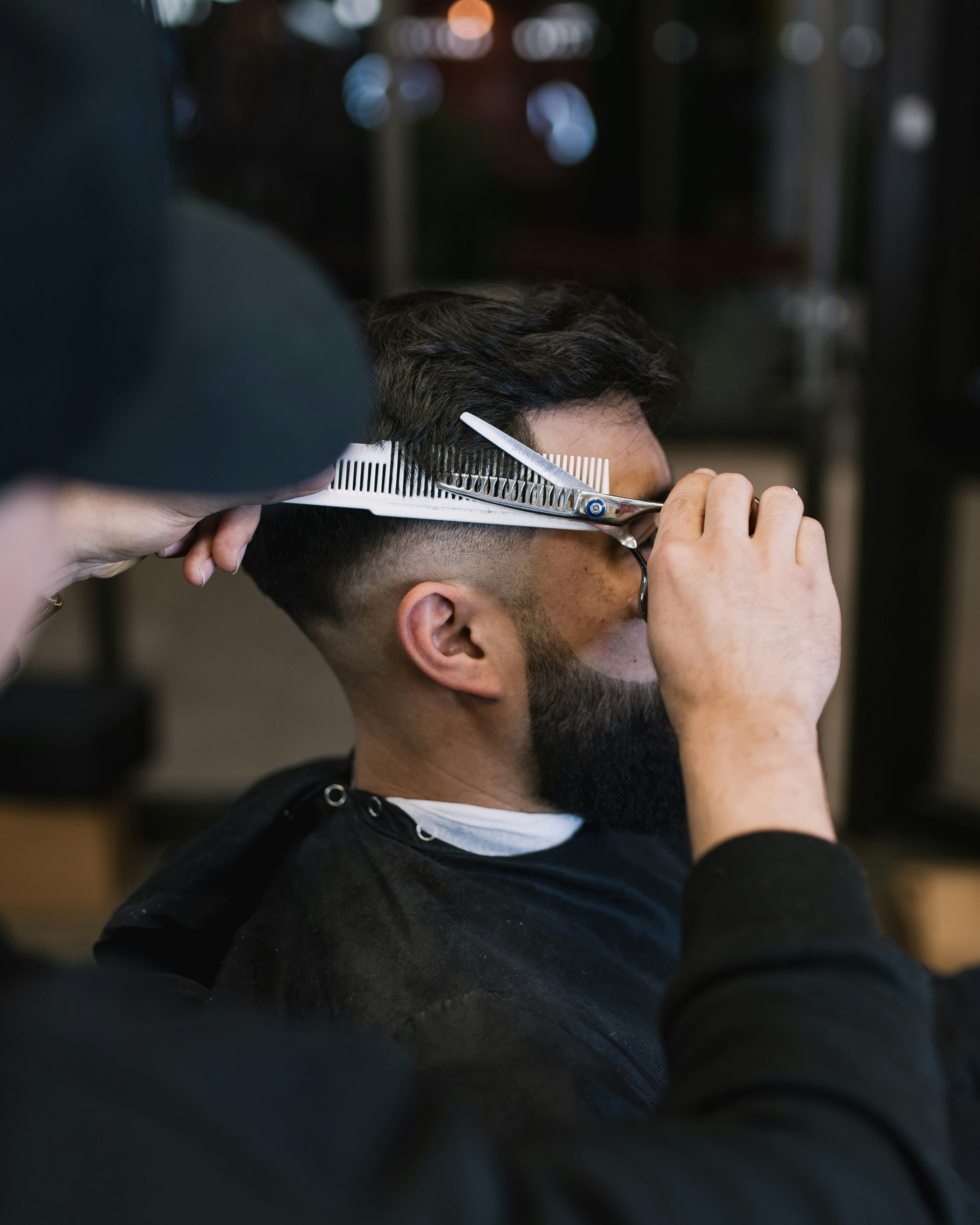 A barber cutting a man's hair with scissors and comb