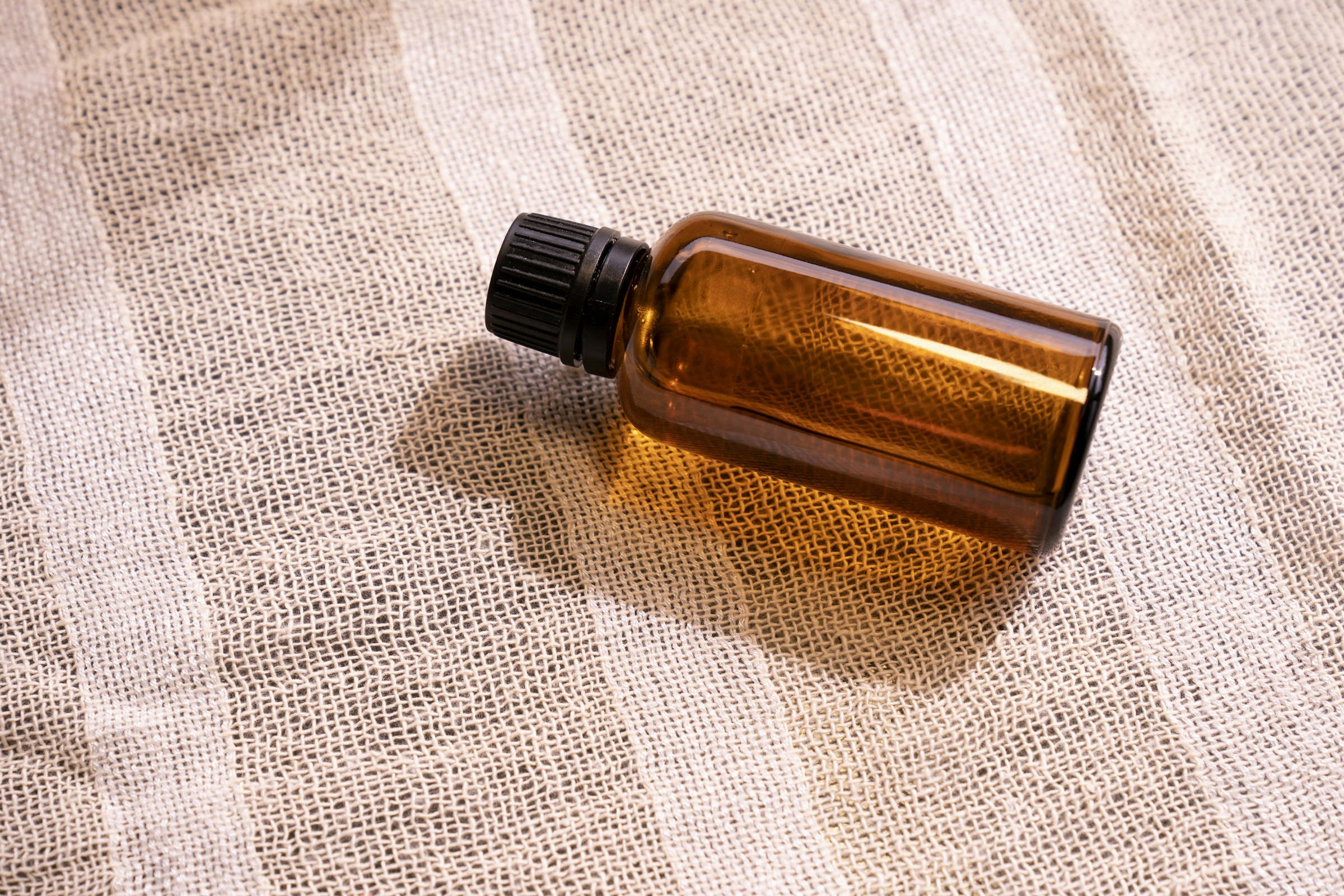 An amber dropper bottle resting on linen