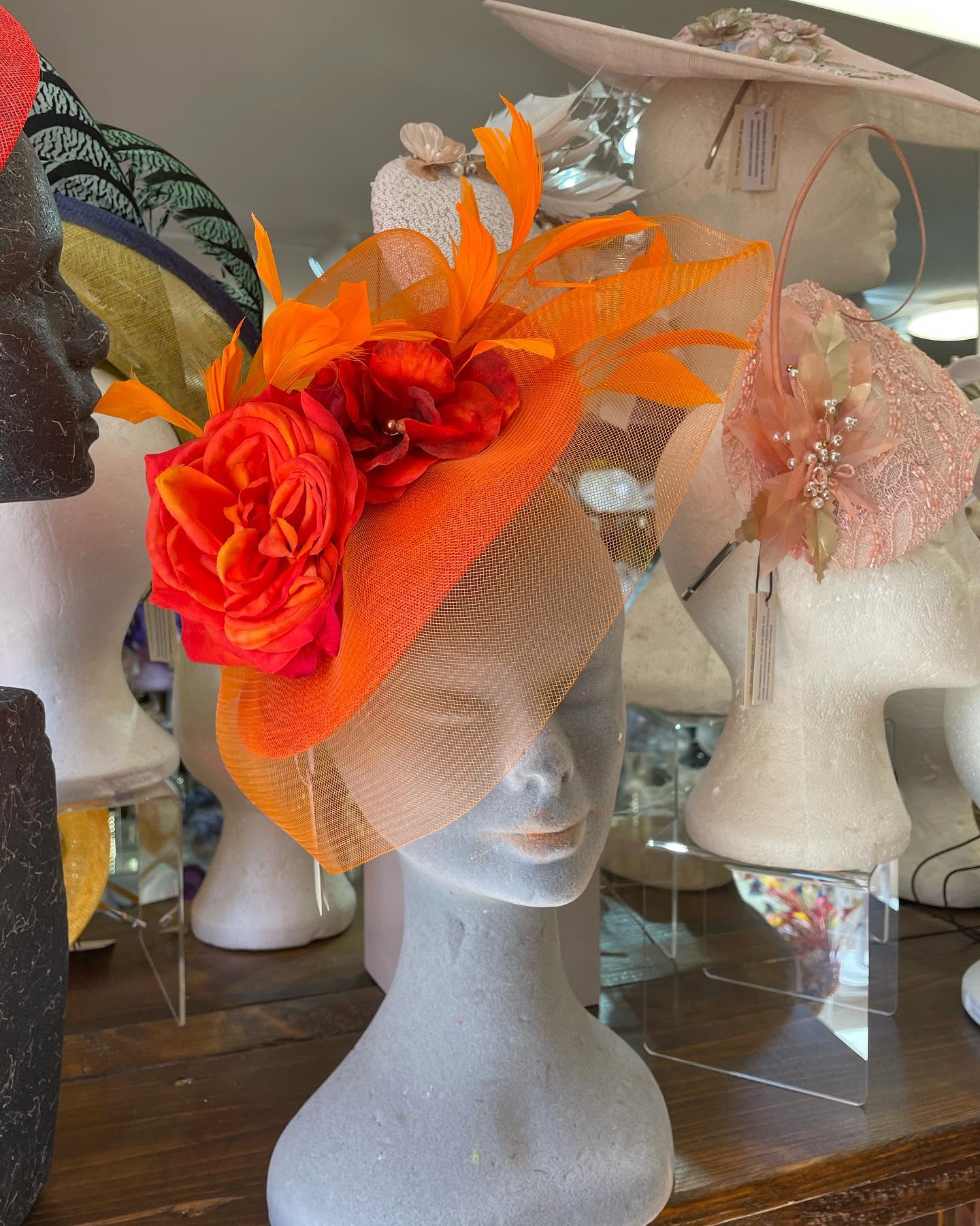 An orange sinamay and feather headpiece with silk roses, from Fiona Rafter's millinery collection