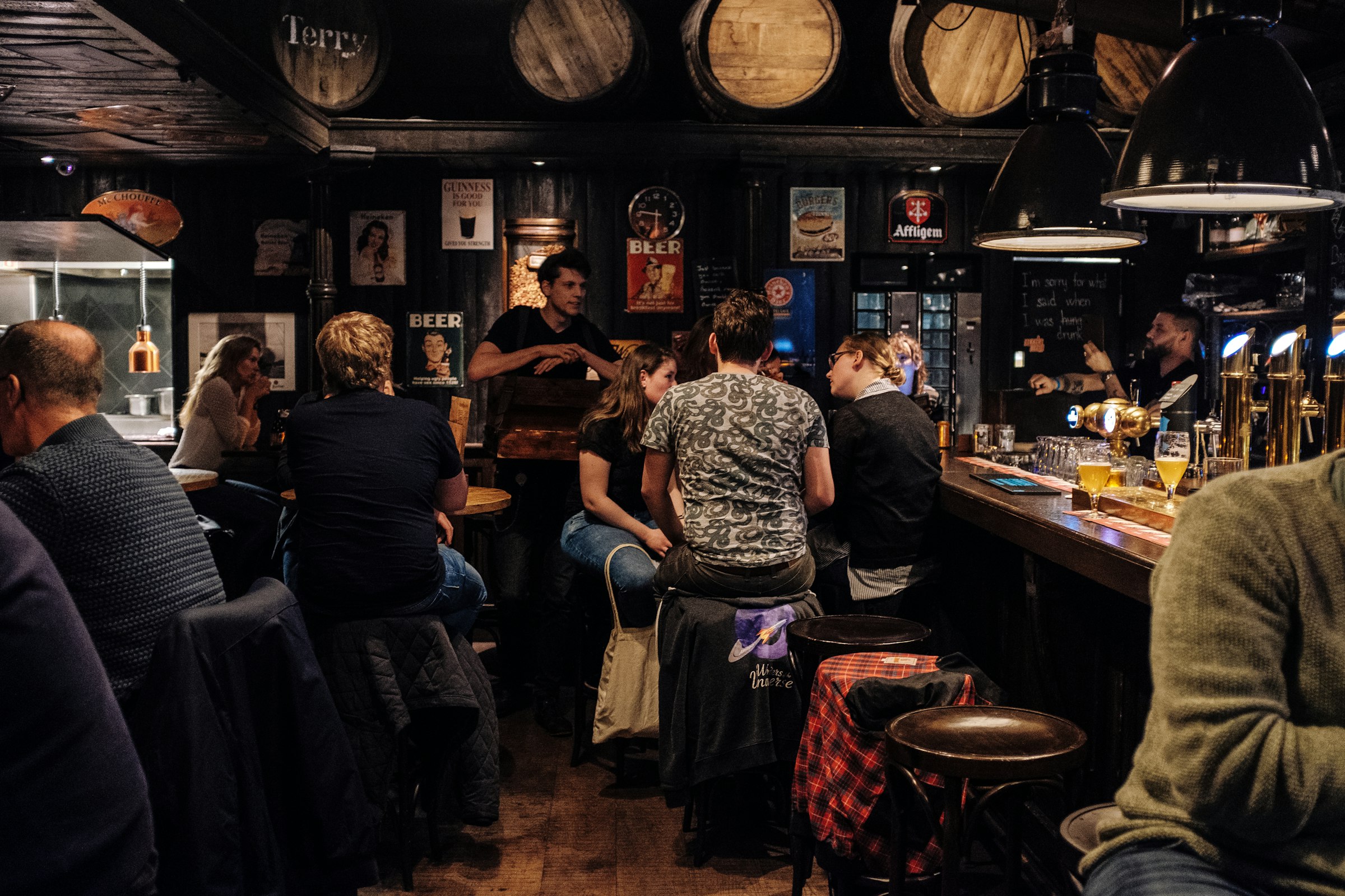 People talking and drinking together along a busy bar