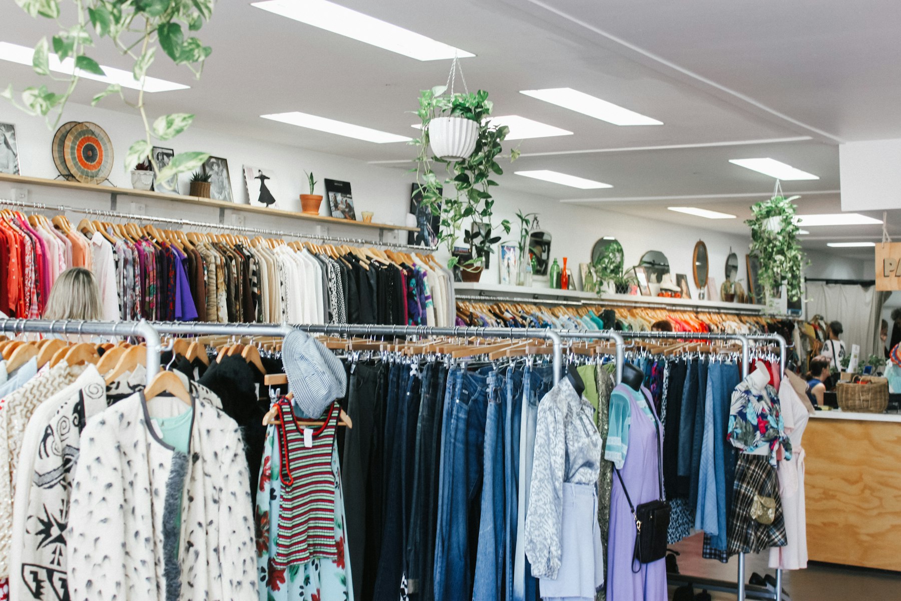 Rails of secondhand clothing filling a bright charity shop interior
