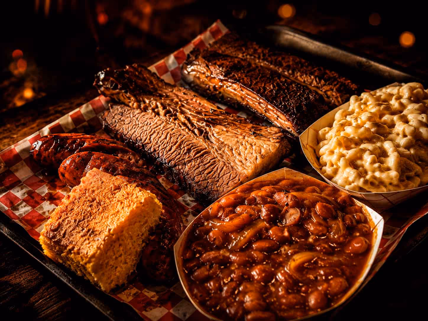 A tray of food with a variety of items including beans, macaroni and cheese, and barbecue.