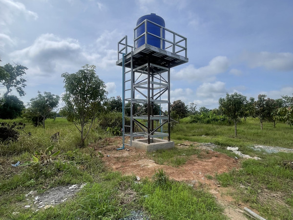 A blue water storage tank on a raised steel tower supplies clean water to families in Cambodia
