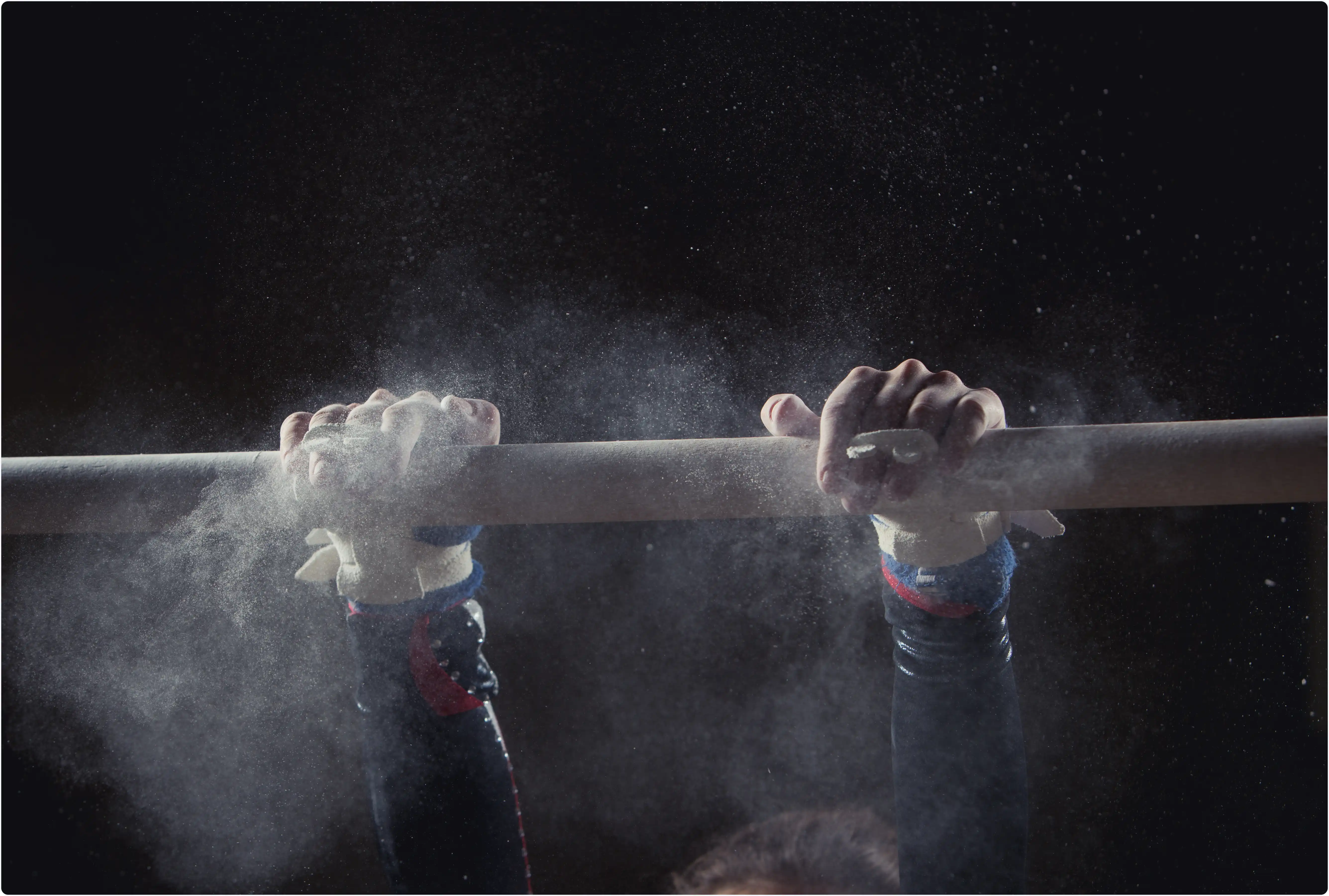 Gymnast chalked hands gripping uneven bars