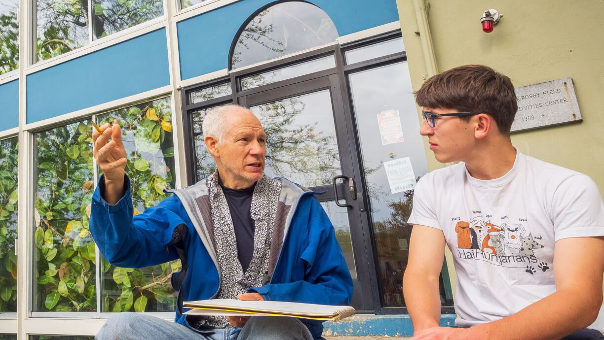 A student and teacher sitting outside and talking at The Cambridge School of Weston (MA).