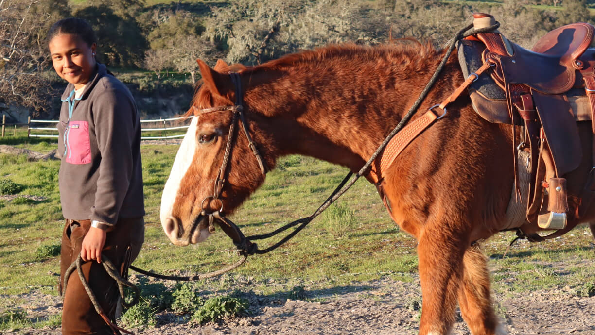 A Midland School (CA) student leading a horse as part of the school's equestrian program.