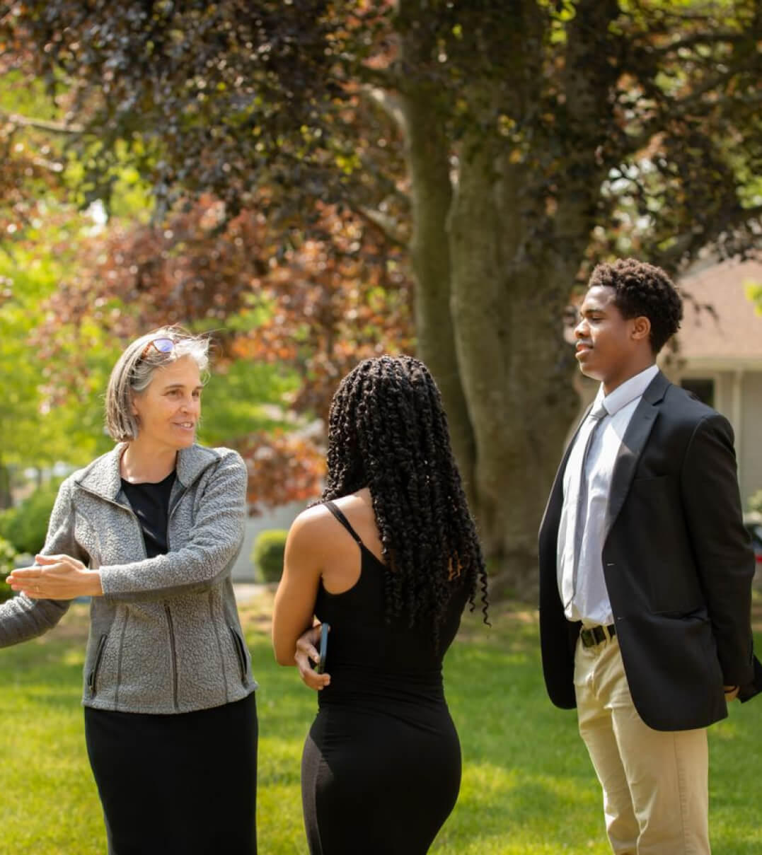 A Tabor faculty member talking to two dressed-up students after a formal event.