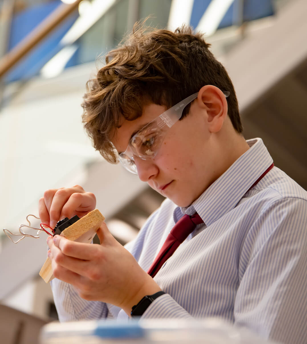 A Fay School student wearing safety glasses working on an electronics project.