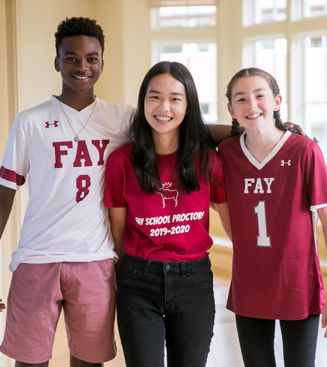 Three Fay School students wearing their sports jerseys and smiling for the camera.