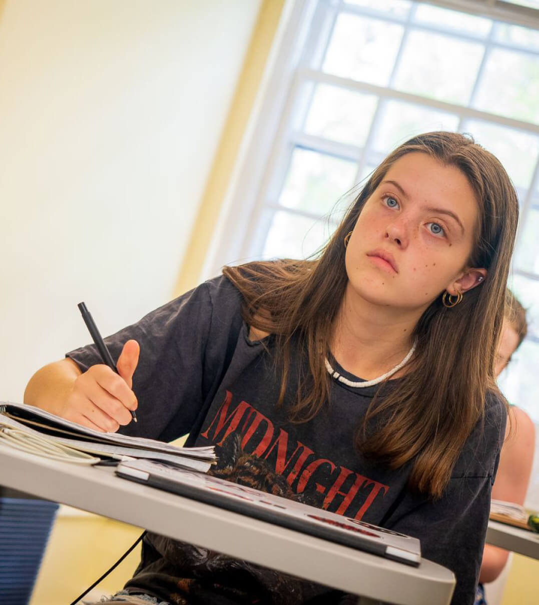 A CSW student at her desk listening intently to the teacher.