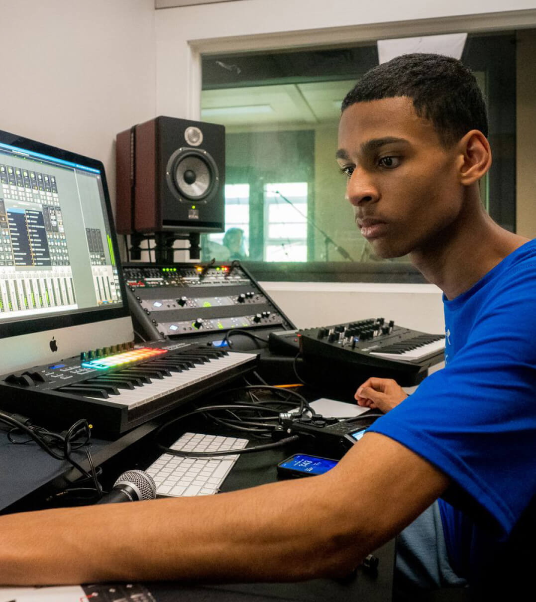 A CSW student working a sound board in a studio.