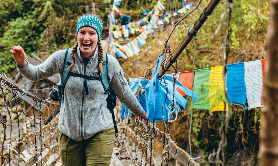 A Baylor School student on a backpacking trip traversing a bridge.
