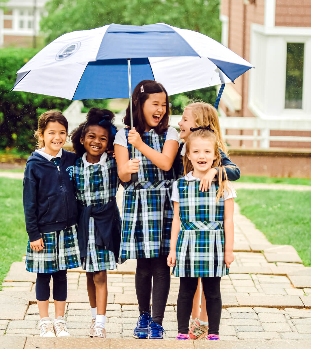 Garrison Forest School elementary students outside holding an umbrella.