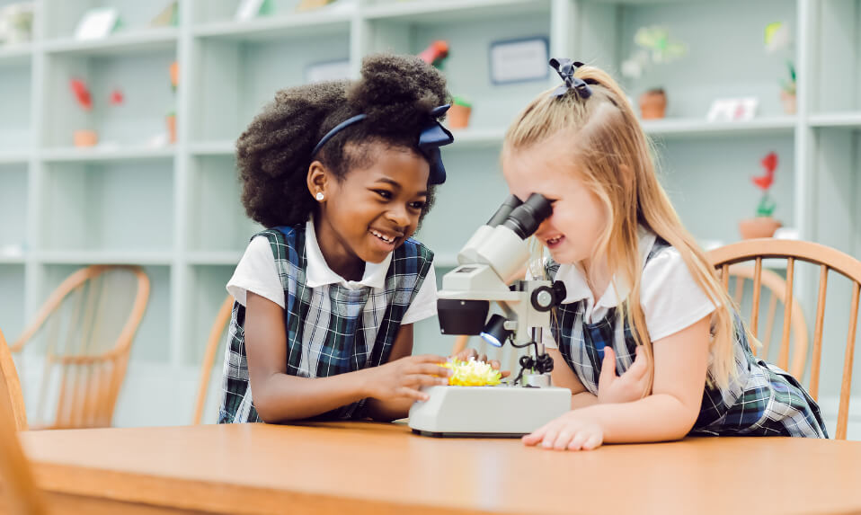Two Garrison Forest School elementary students taking turns looking through a microscope.