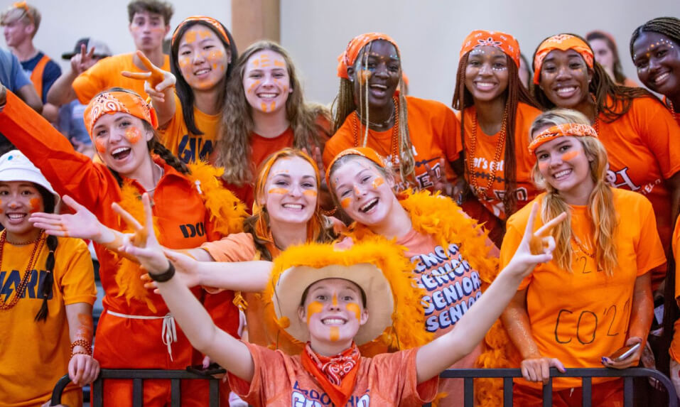 Brook Hill School students dressed in orange cheering at a pep rally.