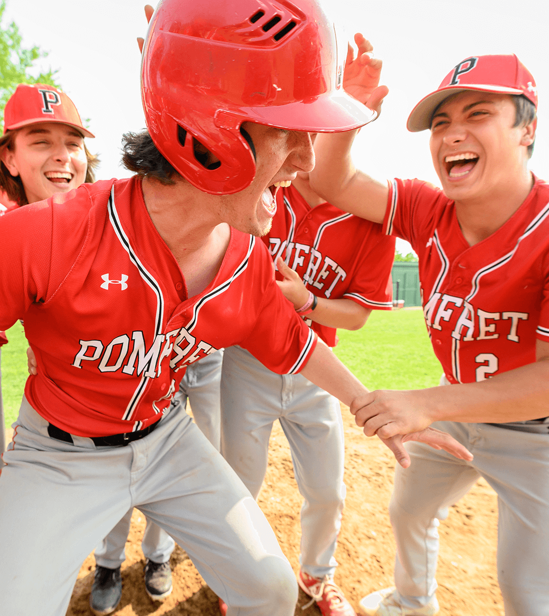 Pomfret School baseball players celebrating a run scored at home plate.