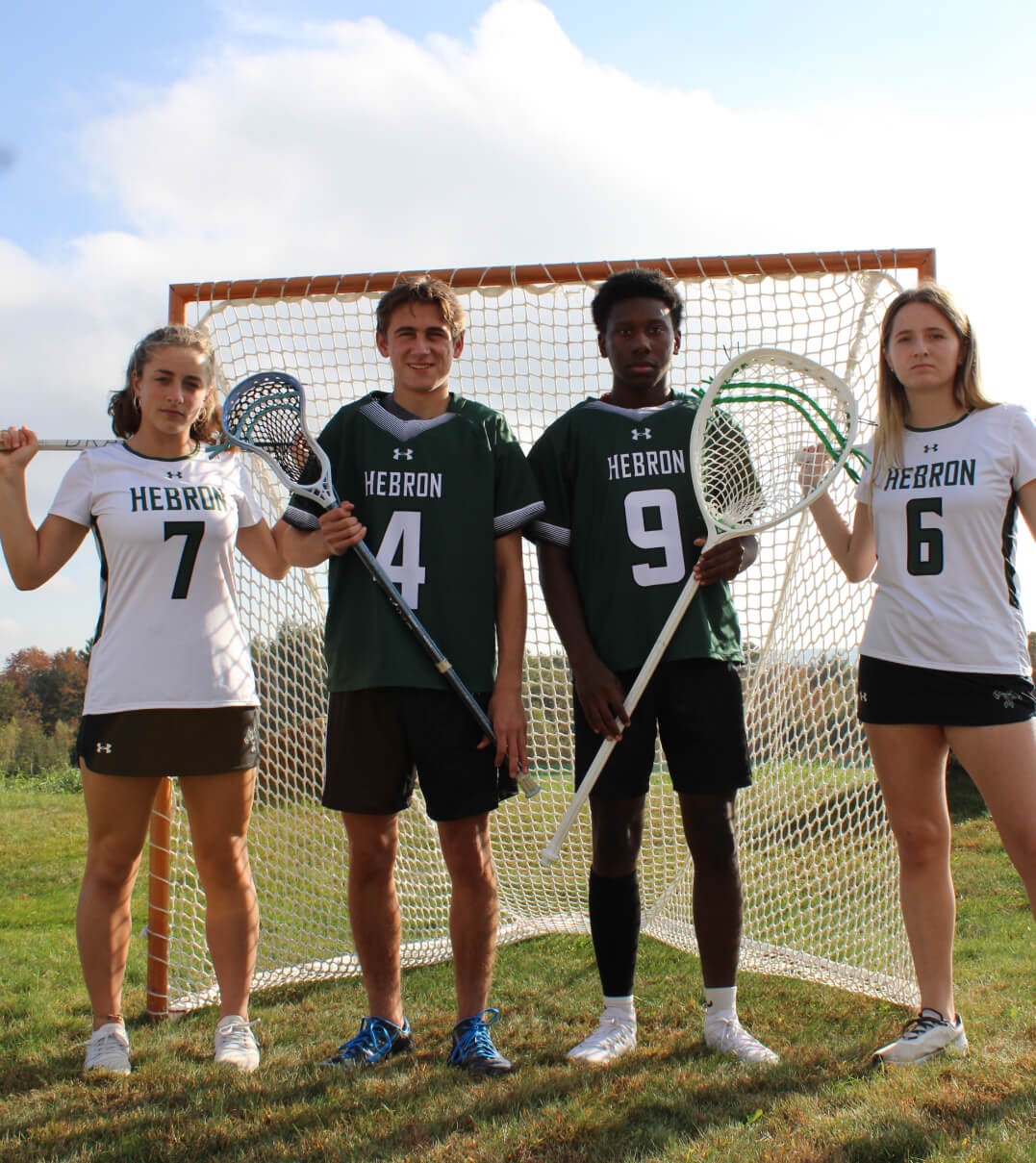 Hebron Academy lacrosse players posing in front of a goal.