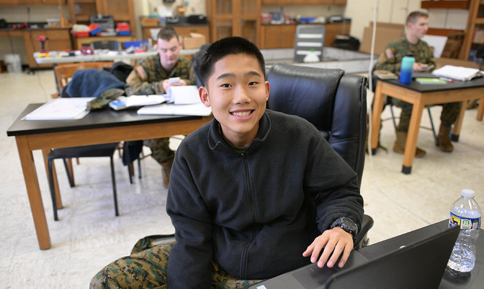 A Fork Union student working on his laptop in a classroom.