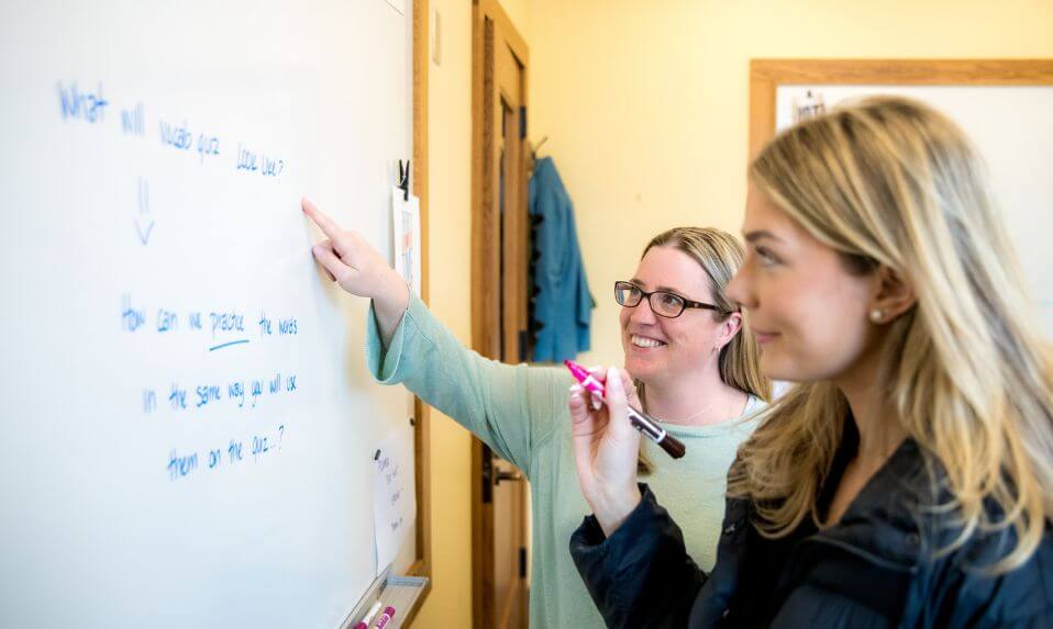 A KUA student working with a teacher on a white board.