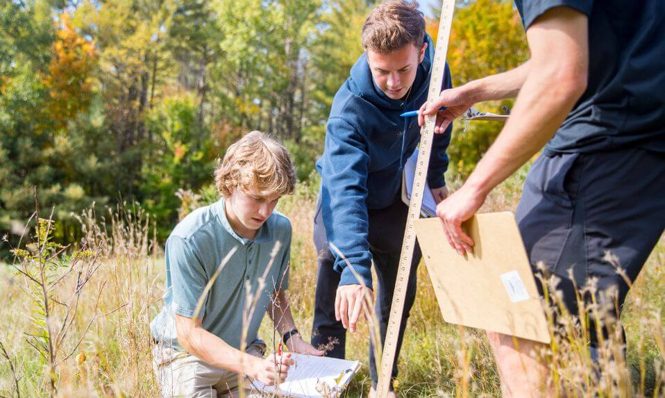 KUA students in a field taking scientific measurements.