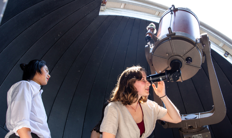 Tabor students in an observatory looking into a telescope.