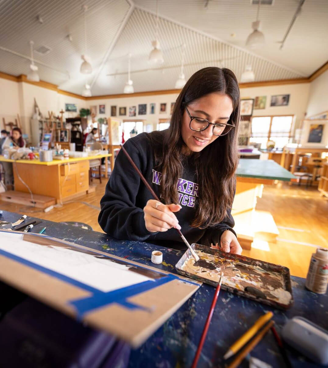 An Ethel Walker art student dipping her brush in paint.
