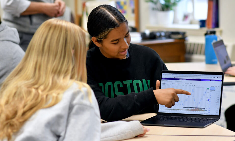 An Ethel Walker student showing another student a graph on her laptop.