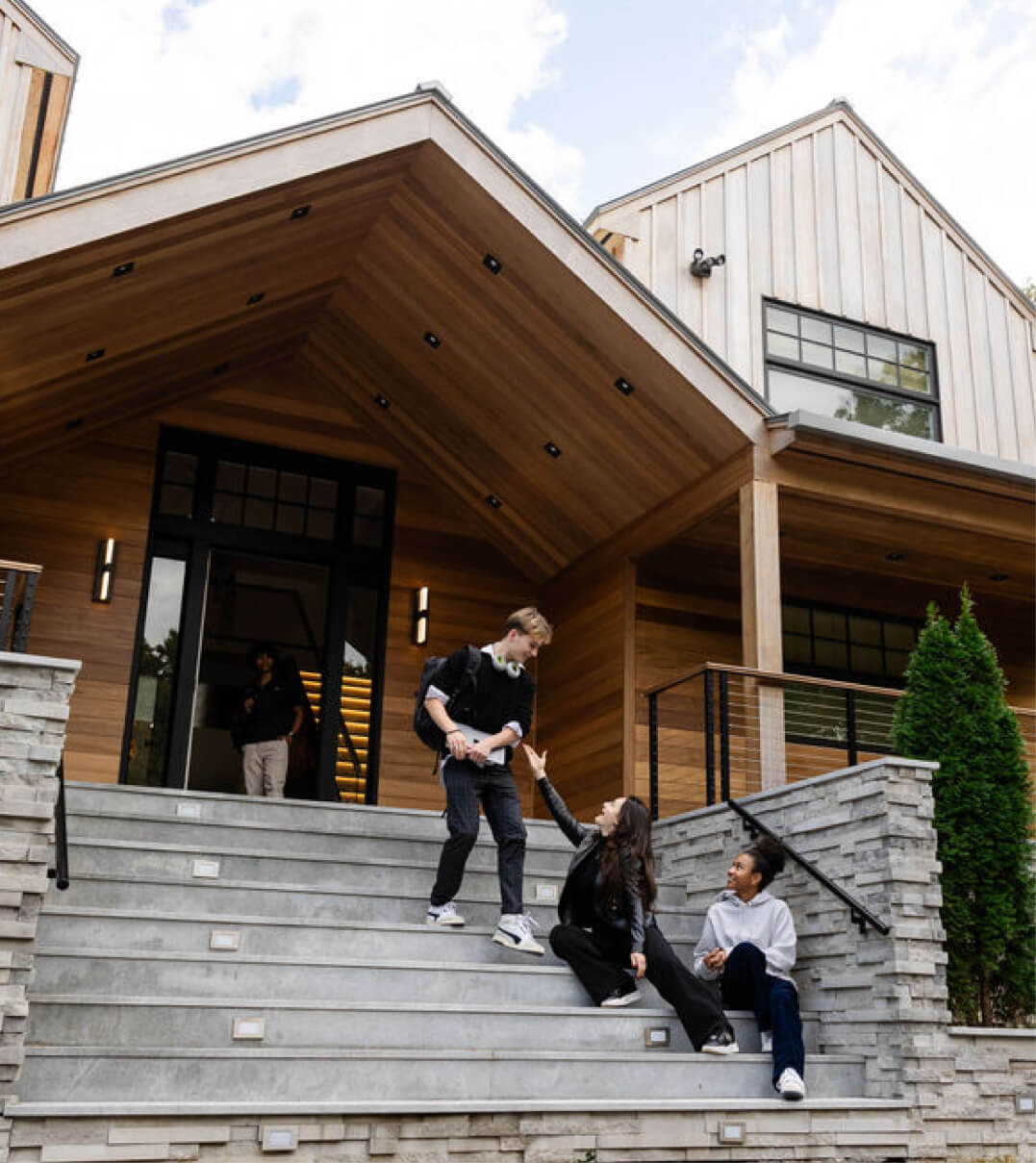 Students sitting on the Ross School steps and greeting an approaching student.
