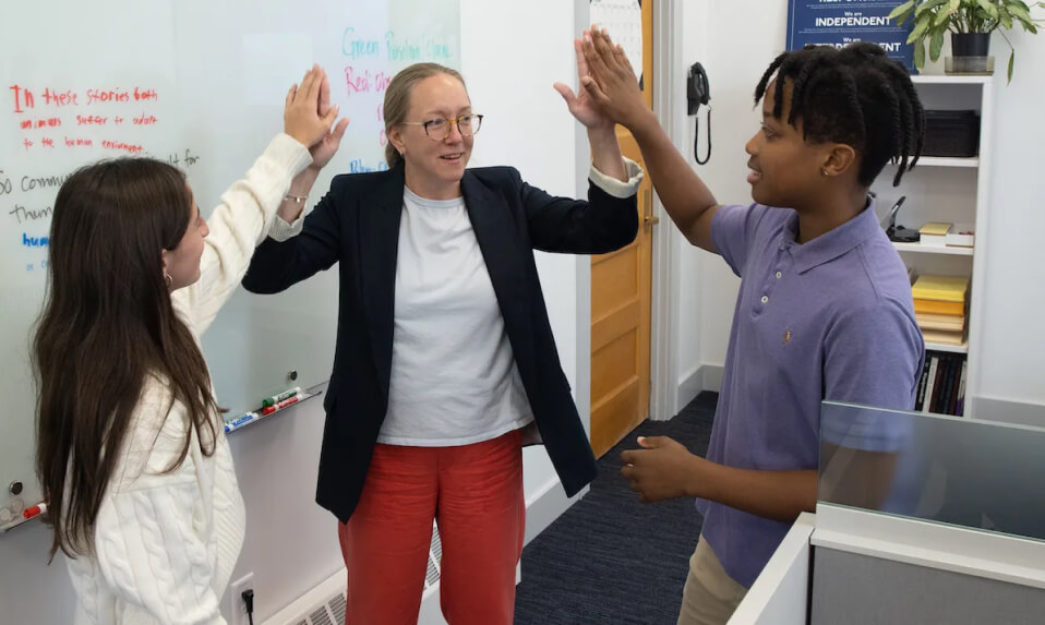 A Brewster teacher high-fiving two students simultaneously.