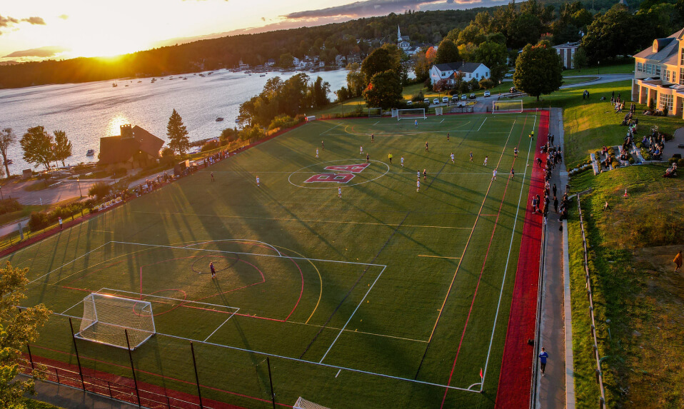An aerial view of a Brewster soccer game at sunset next to the lake.