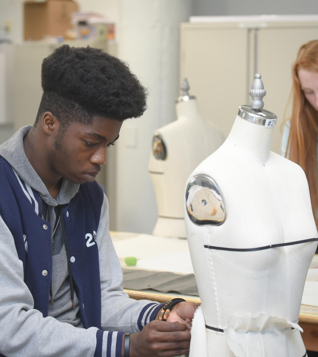 A WMA student affixes fabric to a mannequin in a fashion design course.