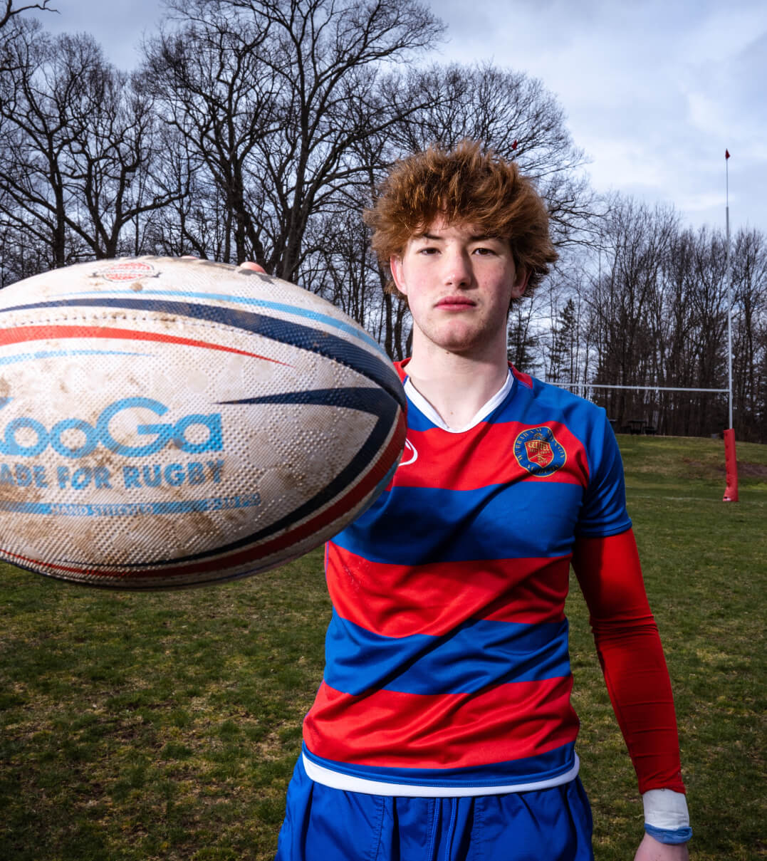 A WMA rugby player holds the ball toward the camera.