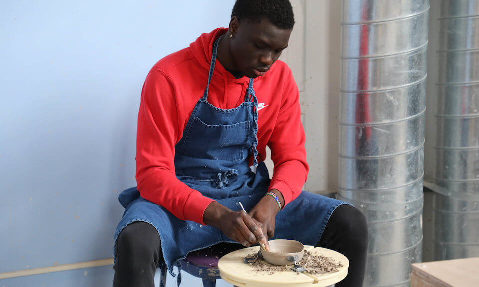 A Proctor student carving a bowl in pottery.