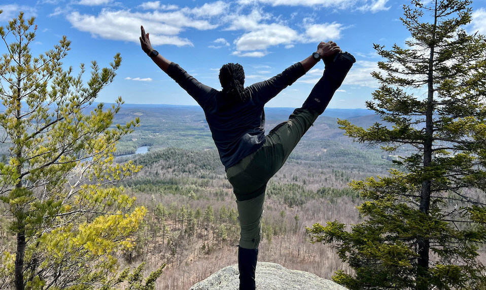 A Proctor student doing a yoga stretch on a mountain scenic lookout.