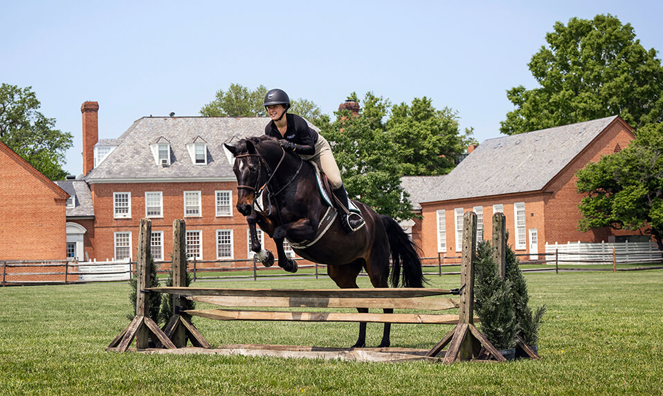 A Foxcroft Student in the equestrian program riding a horse over a jump.