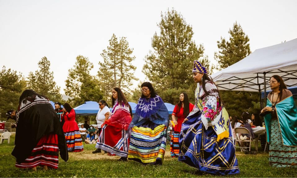 Indigenous teaching artists and Idyllwild students in traditional clothing performing a ceremonial dance.