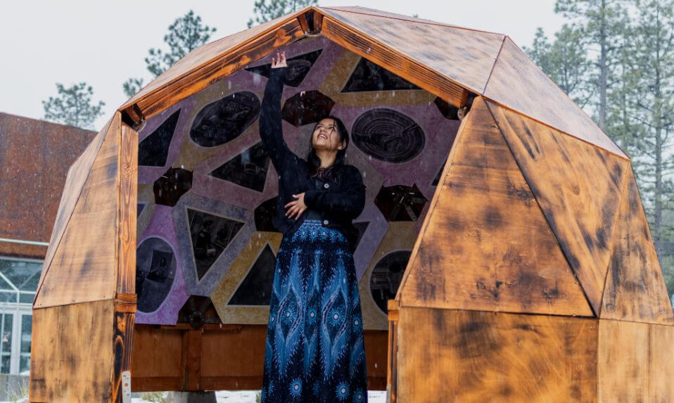An Idyllwild Arts student standing in the sphere-shaped structure during a snowstorm.