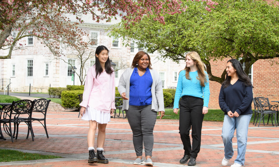 Foxcroft School students walking across campus and talking with their advisor.