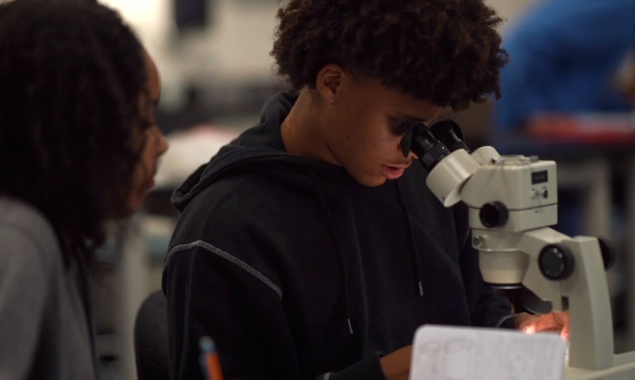 A Crossroads School for the Arts and Sciences (CA) student looking into a microscope.