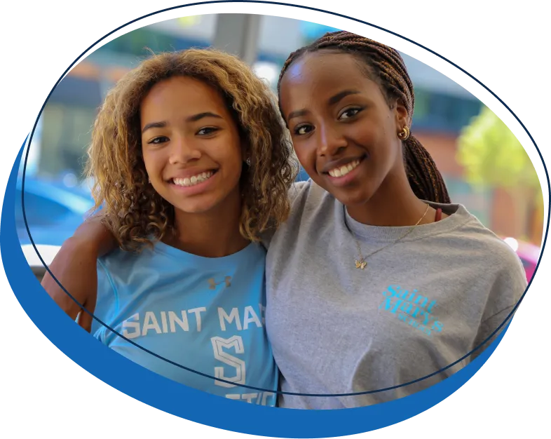 Two Saint Mary's School (NC) students standing with their arms around each other's shoulders and smiling at the camera.
