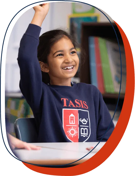 An elementary school student at TASIS England raises her hand in class to ask a question.