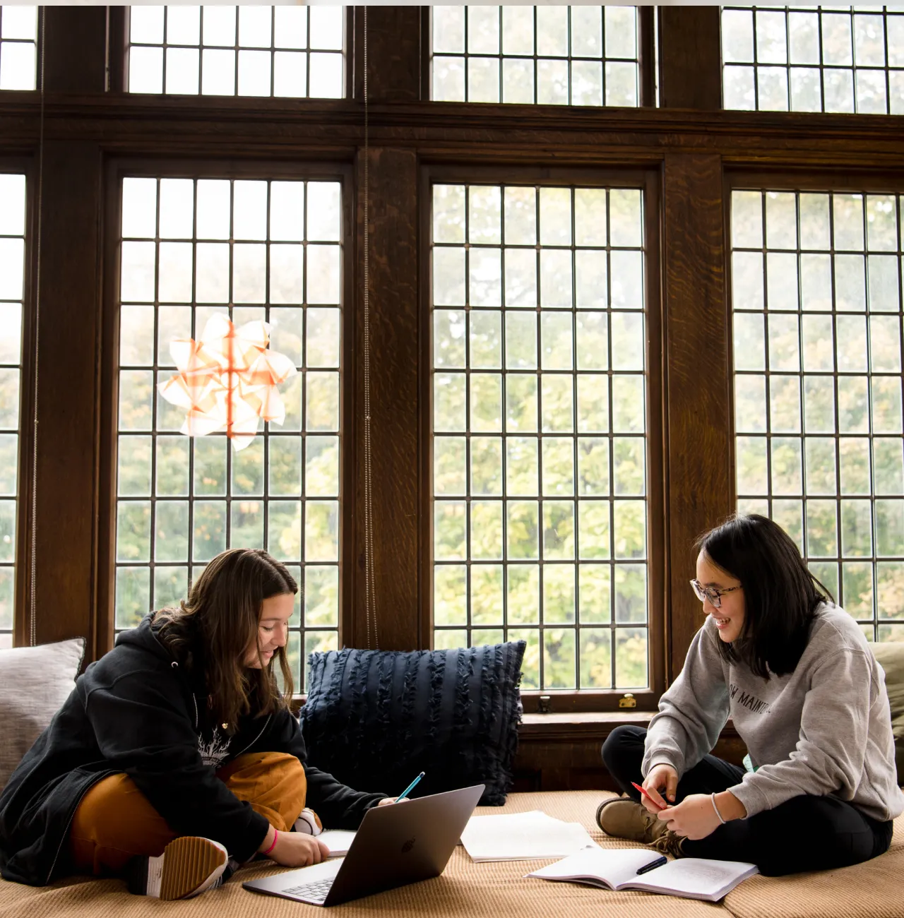 Two students at Emma Willard School studying in front of a large window.