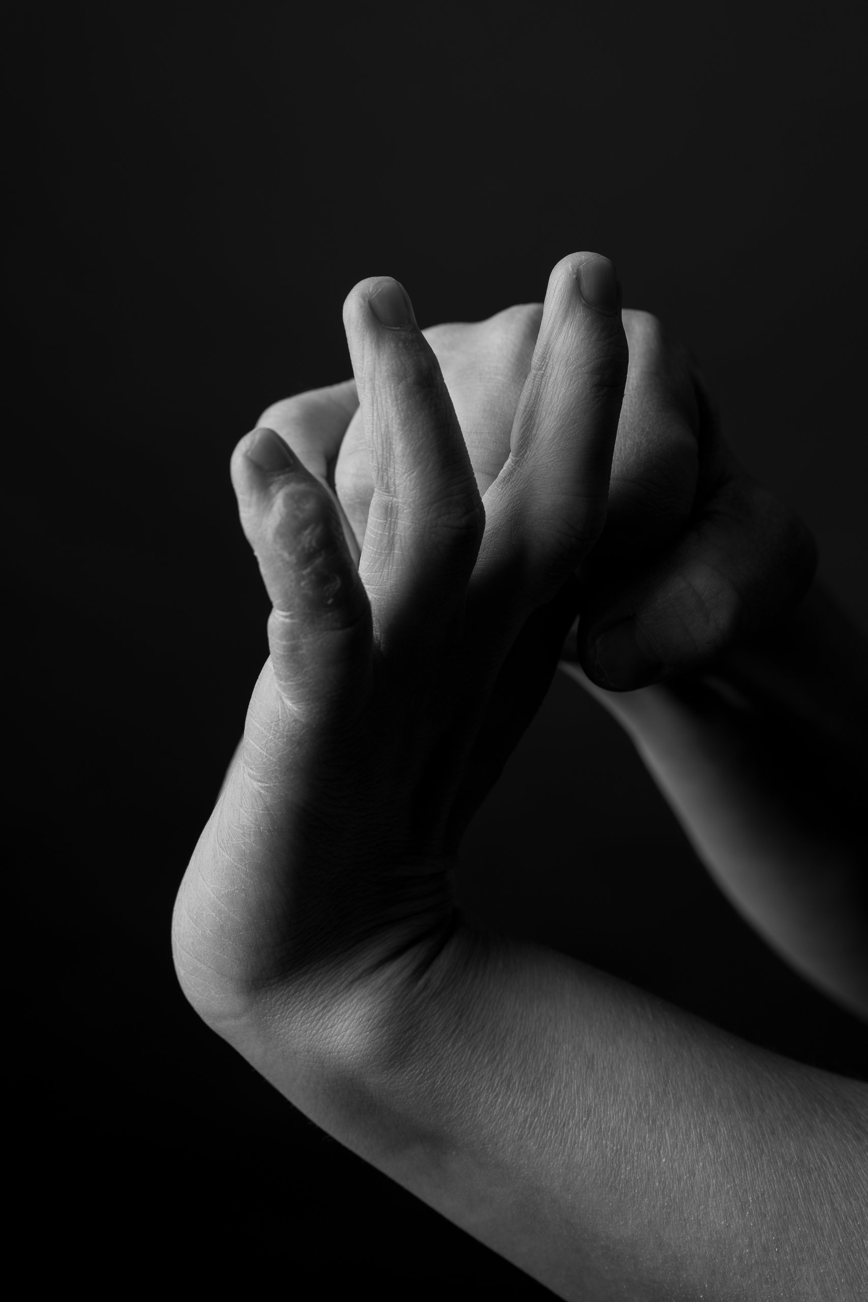 Two hands intertwined against a black background