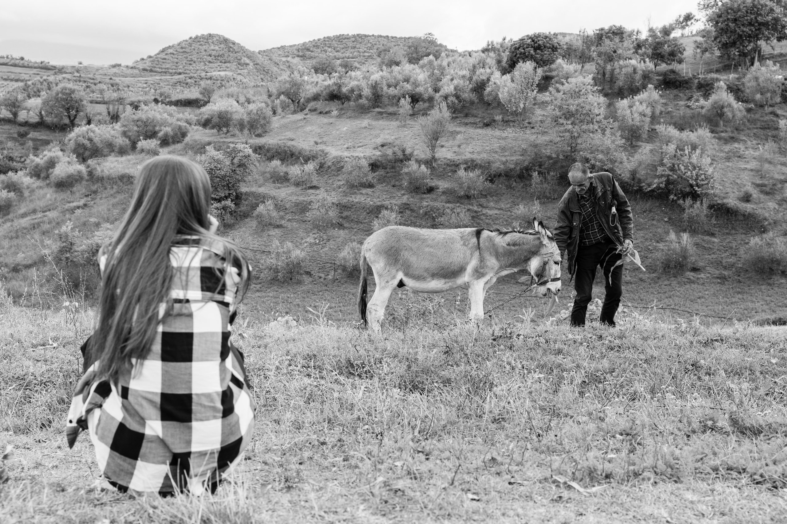 A girl photographing a farmer and his donkey on a hillside in Albania