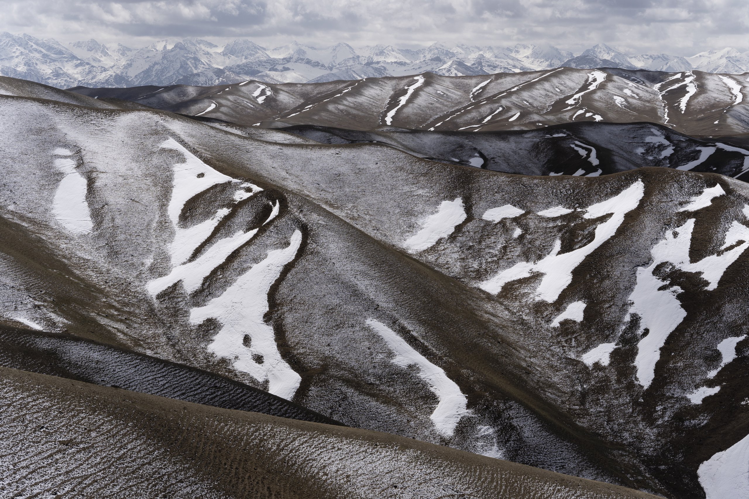 Snow-streaked ridges with high snowy peaks on the horizon